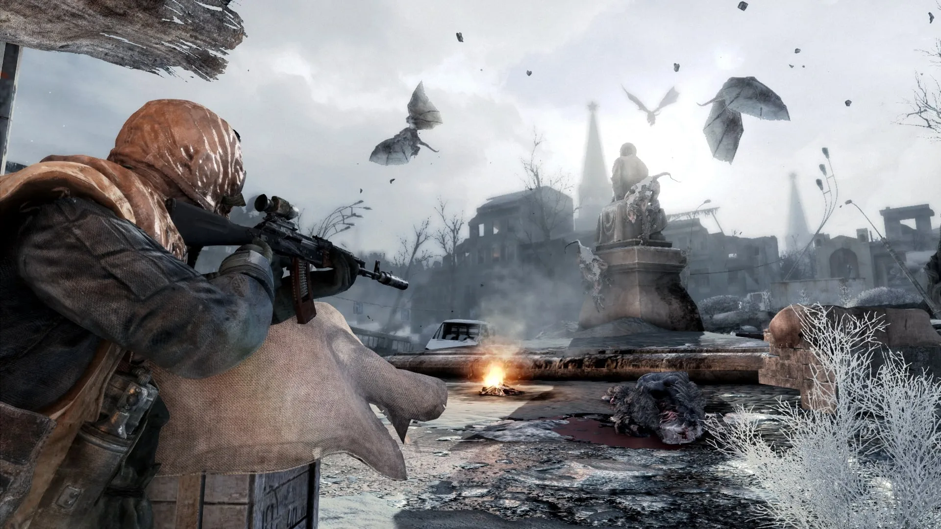 Official Metro 2033 Redux screenshot: a hooded survivor aims a scoped rifle across a frozen, ruined Moscow square while winged mutants circle a statue under a grey sky.