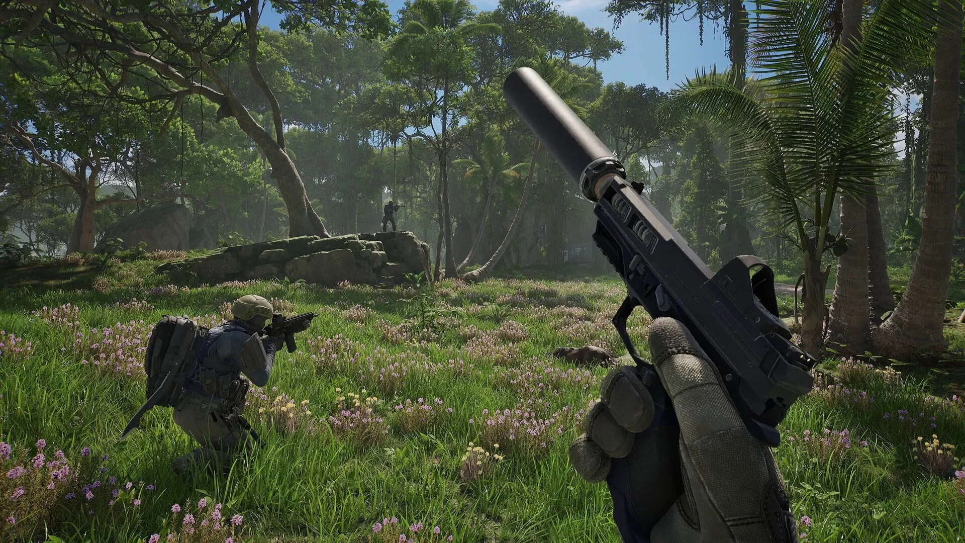 Captura oficial de PUBG: Black Budget: vista en primera persona de una pistola con silenciador en alto en un claro de selva soleado, con un soldado agachado en el pasto y otro de pie sobre una roca más adelante.
